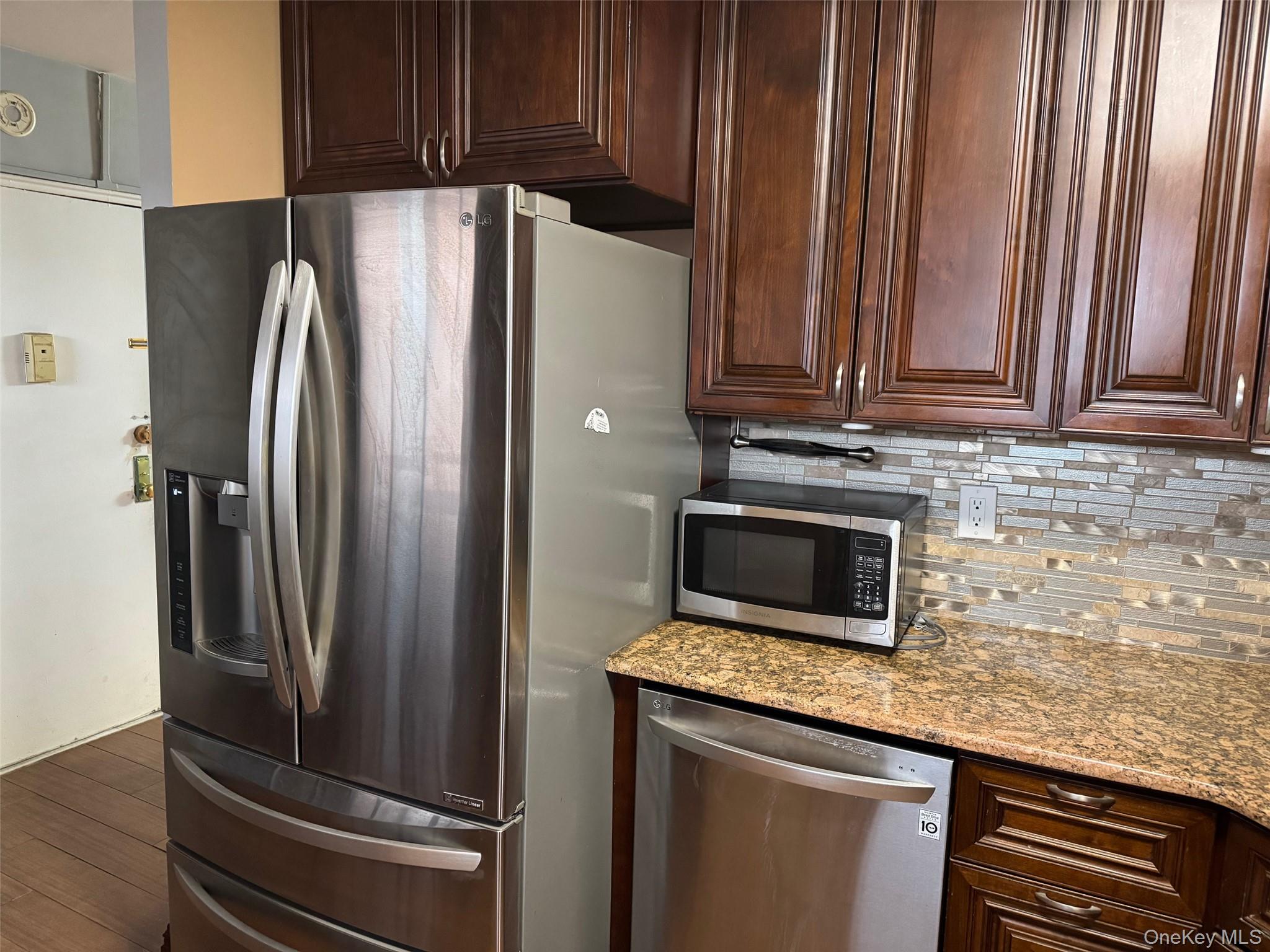 61-55 98th Street, Unit 14L Queens, NY 11374 - Photo 5 of 18 Kitchen featuring dark wood-type flooring, tasteful backsplash, stainless steel appliances, and light stone counters