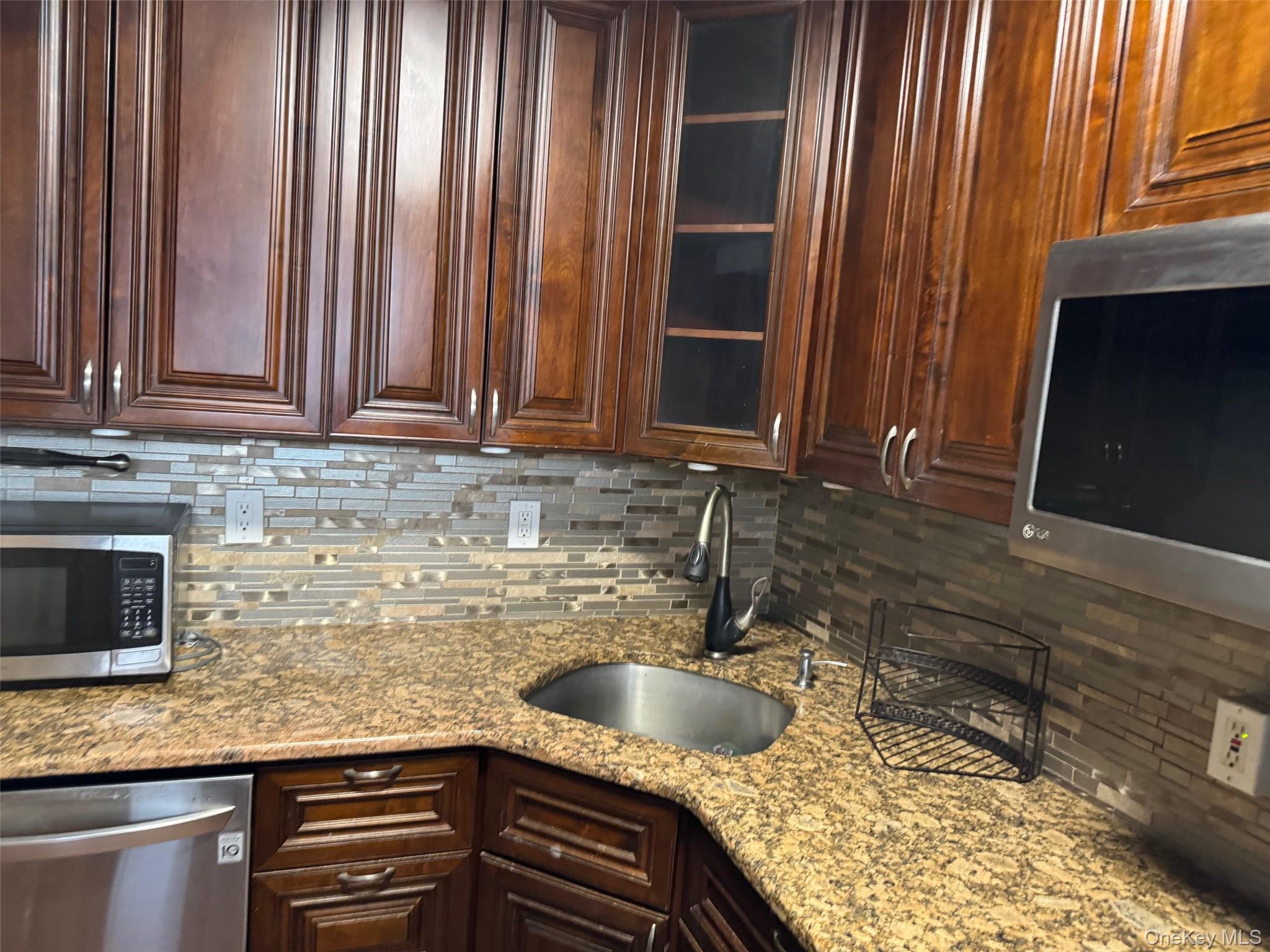 61-55 98th Street, Unit 14L Queens, NY 11374 - Photo 6 of 18 Kitchen with stainless steel appliances, backsplash, light stone counters, and sink