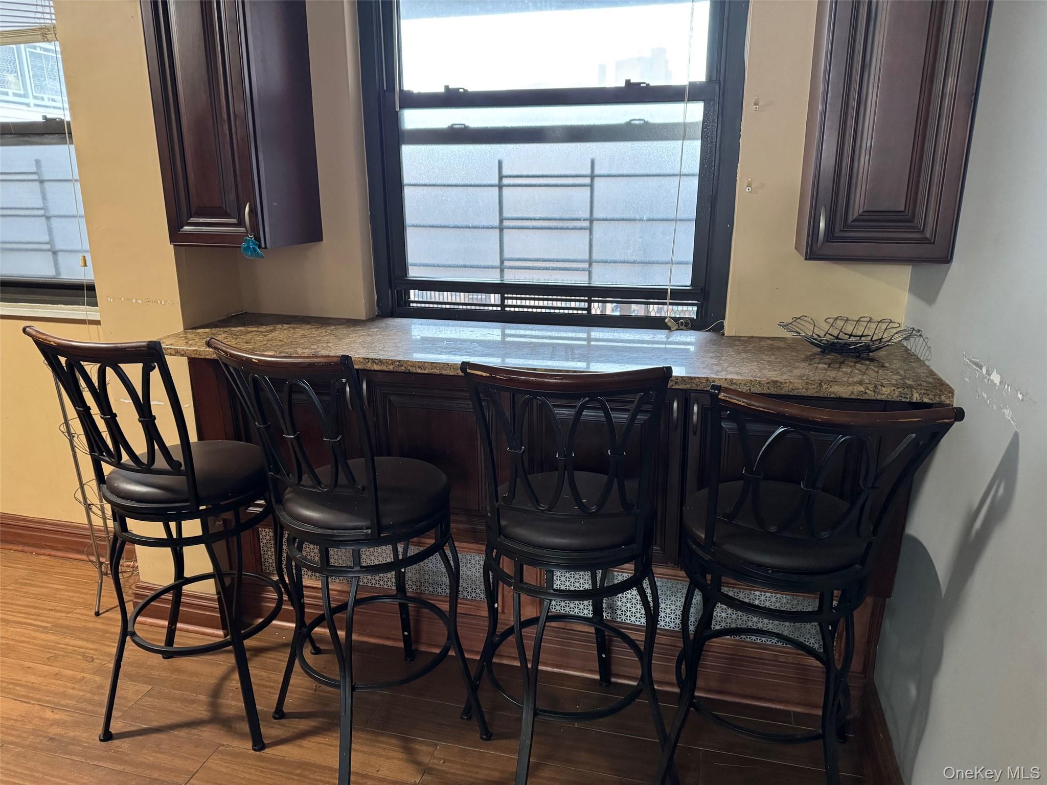 61-55 98th Street, Unit 14L Queens, NY 11374 - Photo 7 of 18 Bar with hardwood / wood-style flooring, dark brown cabinets, and light stone counters