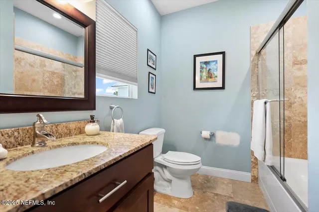a bathroom with a granite countertop toilet sink and mirror