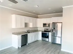 a kitchen with stainless steel appliances granite countertop a stove top oven a sink and a refrigerator with wooden floor