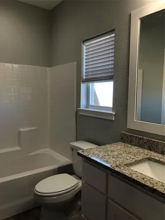 a bathroom with a granite countertop toilet sink and bathtub