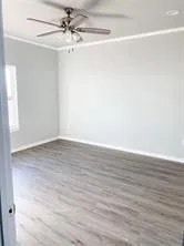 an empty room with wooden floor and fan