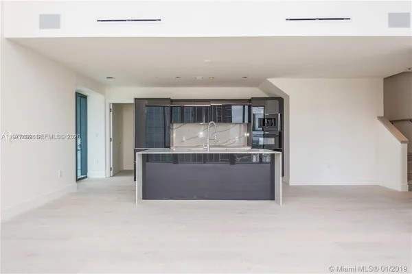 a room with kitchen island granite countertop a stove and a sink