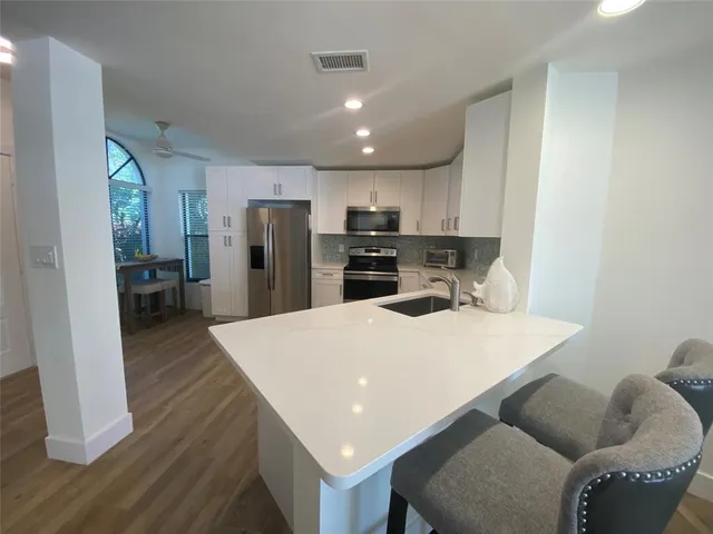 a kitchen with stainless steel appliances a refrigerator a sink dishwasher a stove and a refrigerator with wooden floor