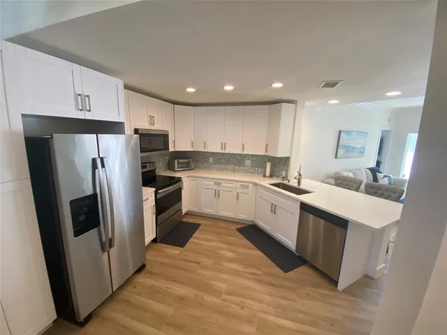 a kitchen with white cabinets stainless steel appliances and a refrigerator