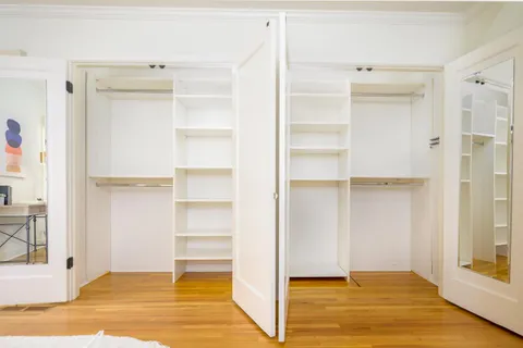 a view of an empty room with wooden floor and closet