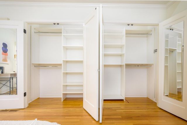 a view of an empty room with wooden floor and closet