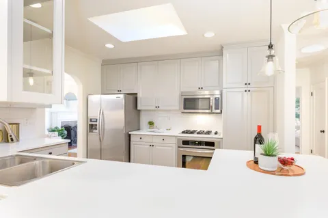 a kitchen with stainless steel appliances kitchen island granite countertop a refrigerator a stove and a sink with wooden floor