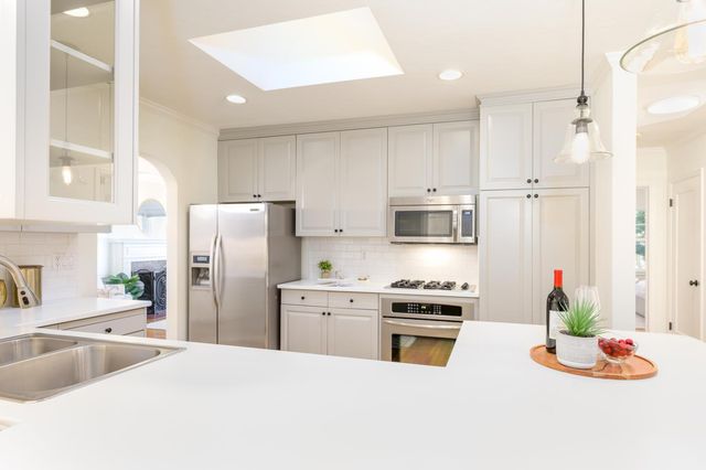 a kitchen with stainless steel appliances kitchen island granite countertop a refrigerator a stove and a sink with wooden floor