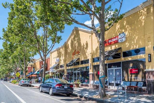a store with buildings and cars parked on the road