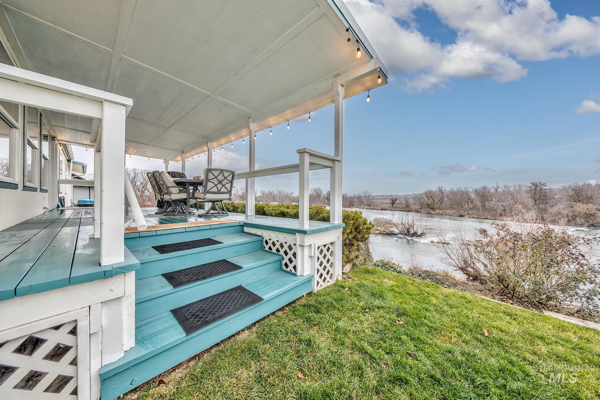 Wooden deck featuring a water view, a yard, outdoor dining space, and a sunroom