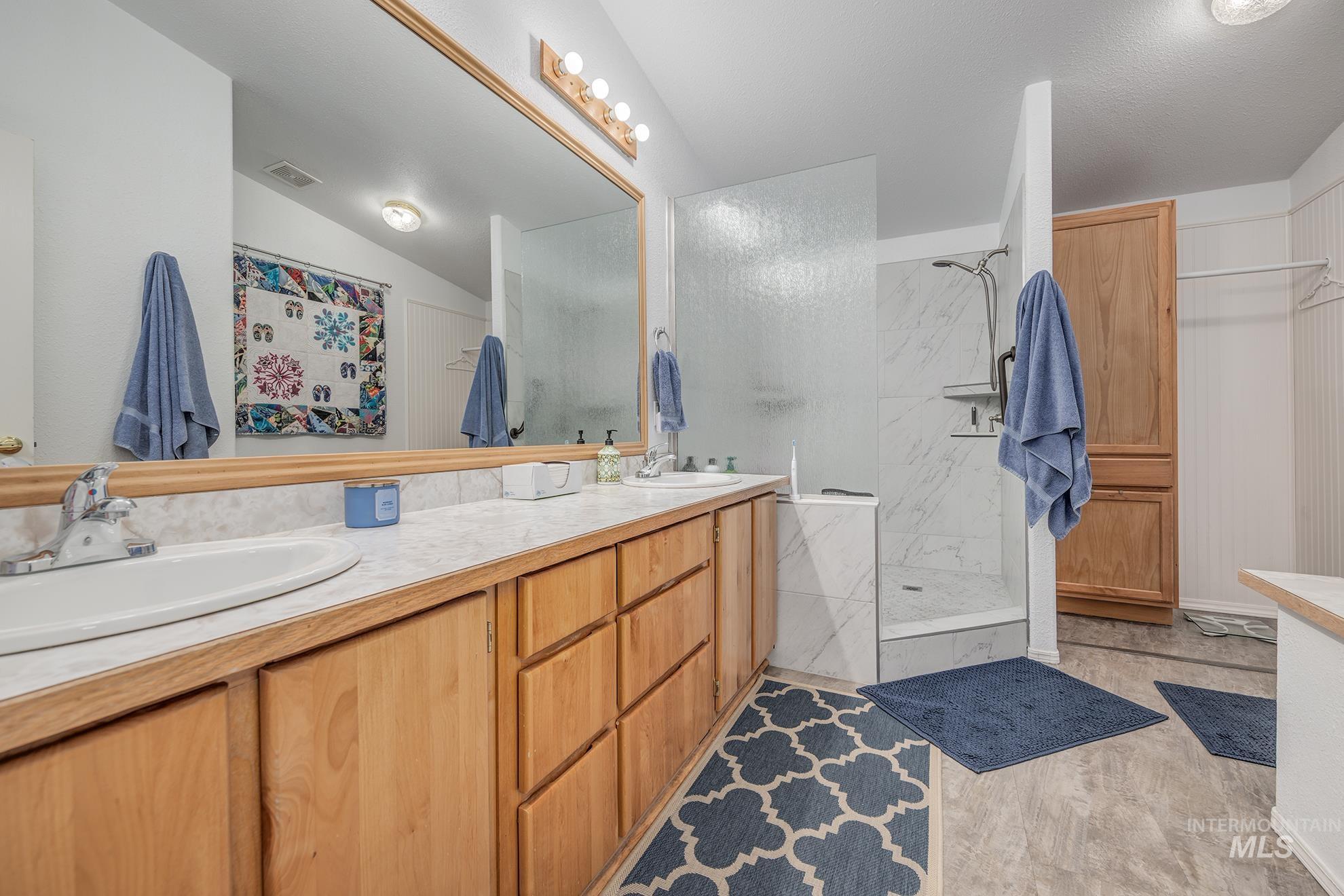 2750 Alden Road, Unit 27 Fruitland, ID 83619 - Photo 21 of 45 Bathroom featuring double vanity, a marble finish shower, light wood-type flooring, and lofted ceiling