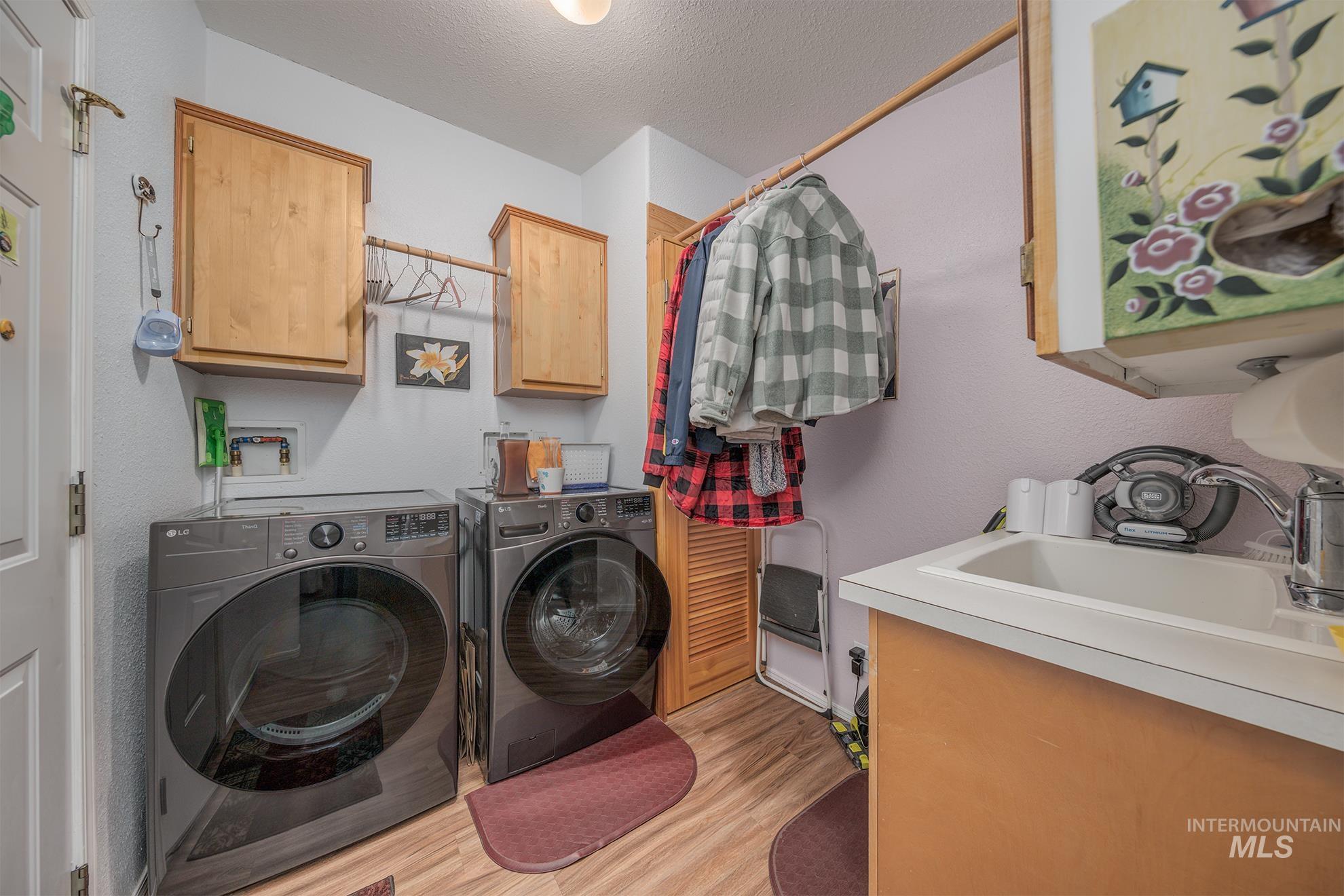 2750 Alden Road, Unit 27 Fruitland, ID 83619 - Photo 30 of 45 Washroom with cabinet space, a textured ceiling, washer and clothes dryer, and light wood-style floors