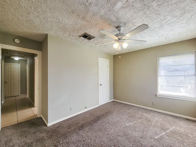 an empty room with windows and fan