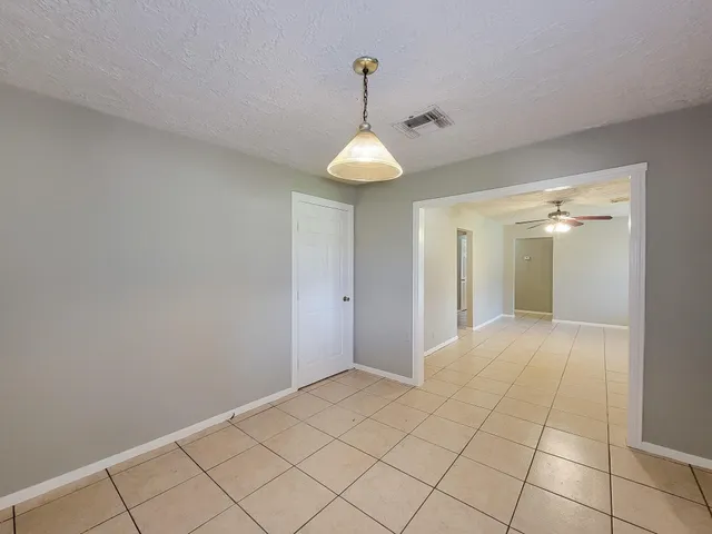 a view of an empty room and window and chandelier fan