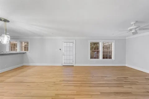 a view of an empty room with a window and wooden floor