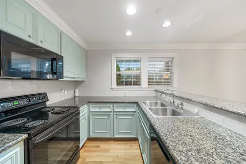 a large kitchen with granite countertop a sink and a refrigerator