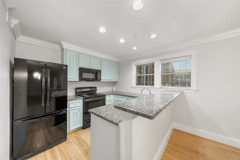 a view of kitchen with stainless steel appliances wooden floor and large window