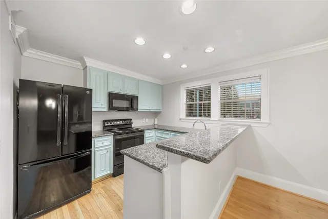 a view of kitchen with stainless steel appliances wooden floor and large window