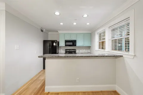 a view of an empty room with wooden floor and a ceiling fan