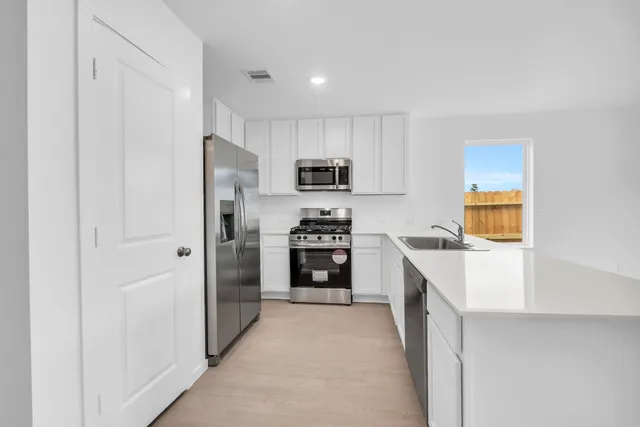 a kitchen with granite countertop a refrigerator and a stove top oven
