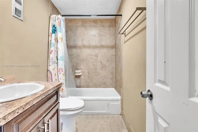 a bathroom with a granite countertop bathtub shower sink vanity and toilet