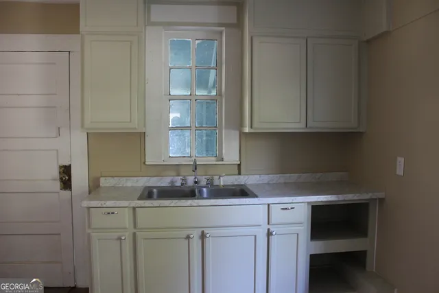 a kitchen with granite countertop white cabinets and sink