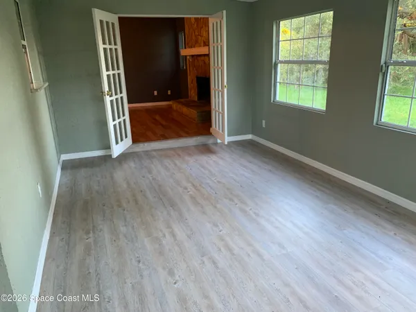 an empty room with wooden floor and windows