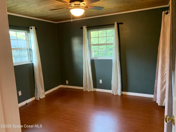 an empty room with wooden floor and windows