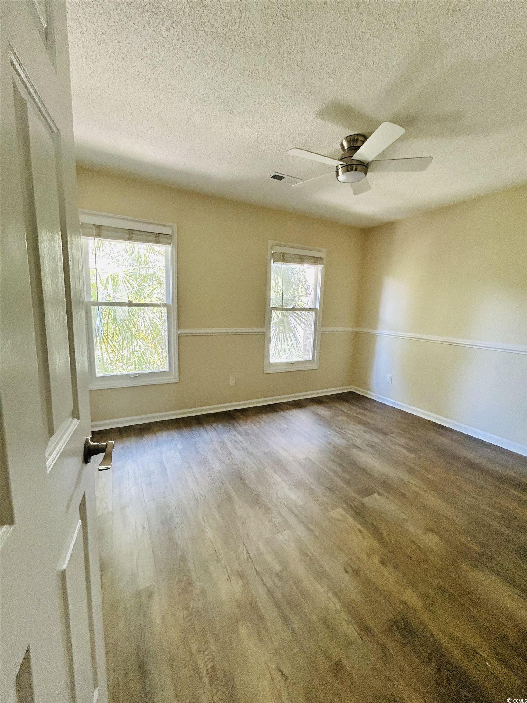 306 76th Avenue North, Unit B2 Myrtle Beach, SC 29572 - Photo 3 of 6 Empty room with a textured ceiling, wood finished floors, and a ceiling fan