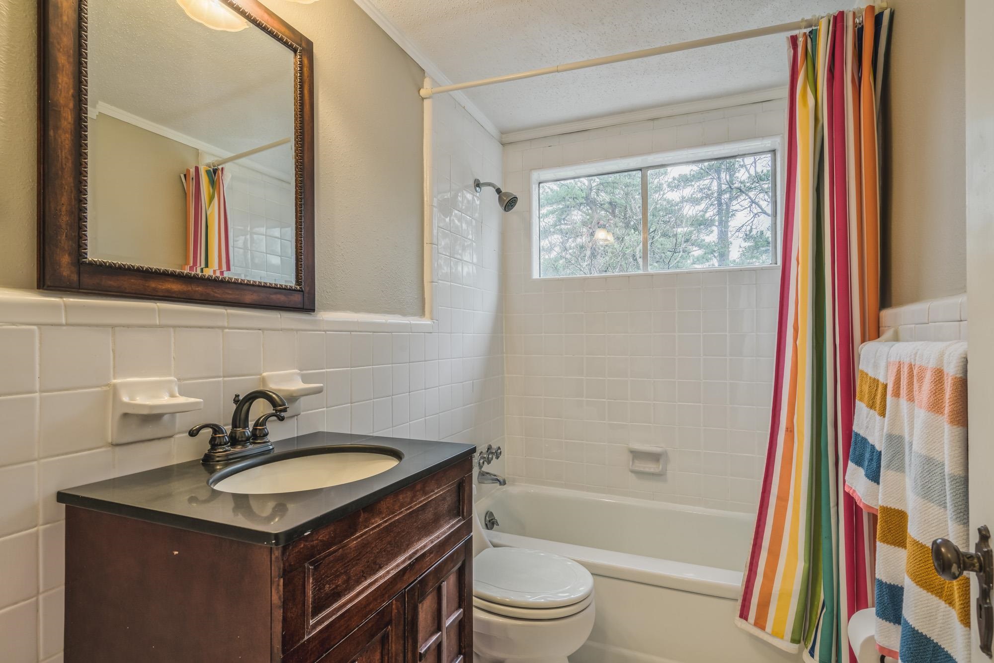 4518 Sequoia Road Memphis, TN 38117 - Photo 18 of 25 a bathroom with a granite countertop sink toilet a mirror a vanity and a shower