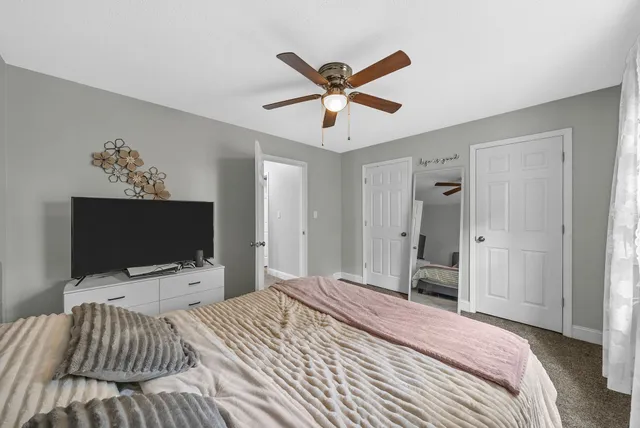 a bedroom with a bed and a flat tv screen on dresser