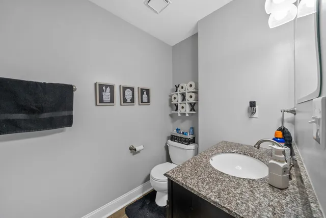 a bathroom with a granite countertop sink a toilet and a mirror