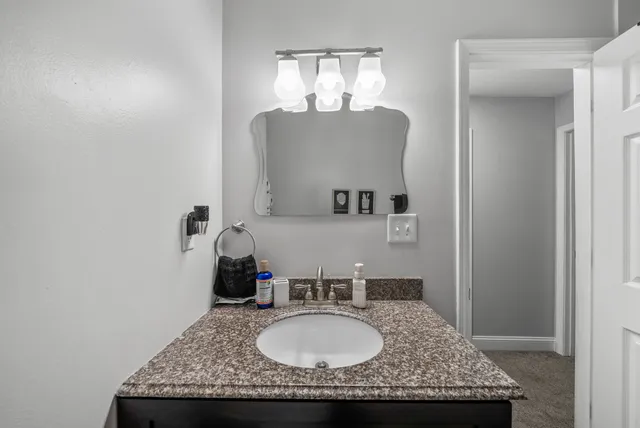 a bathroom with a granite countertop sink a mirror and vanity