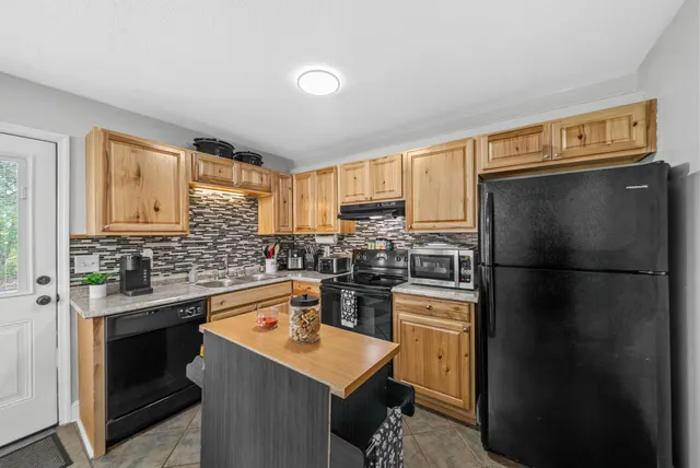 a kitchen with a refrigerator a stove a sink dishwasher and wooden cabinets with wooden floor