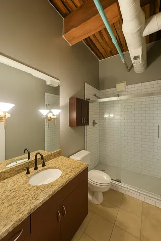 a bathroom with a granite countertop sink a toilet and shower