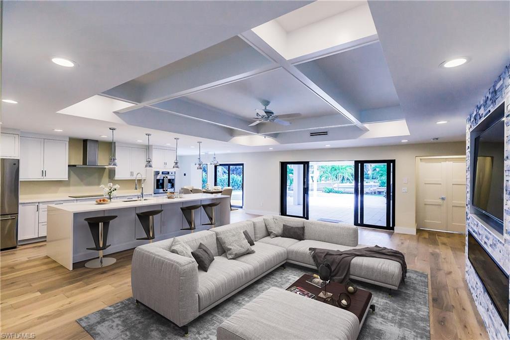 a living room with furniture kitchen view and a flat screen tv