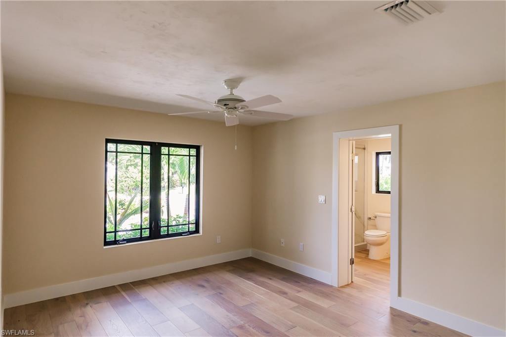 1300 Dolphin Road Naples, FL 34102 - Photo 11 of 22 an empty room with wooden floor chandelier and windows