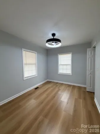 a view of an empty room with window and wooden floor
