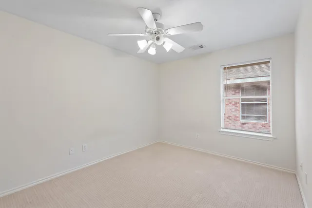 an empty room with a chandelier fan and windows