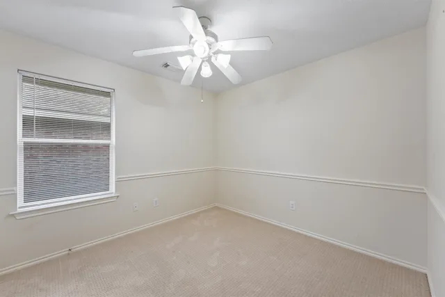 an empty room with a window and a fan
