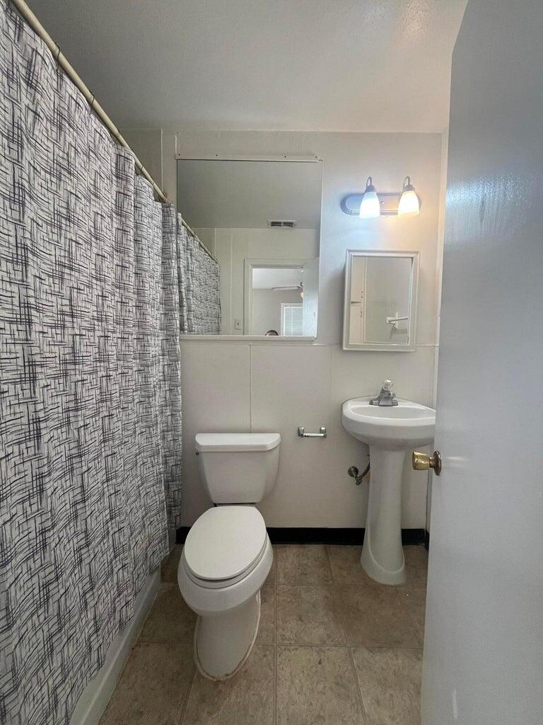 3113 33rd Street, Unit A Lubbock, TX 79410 - Photo 6 of 10 a bathroom with a toilet a sink and mirror