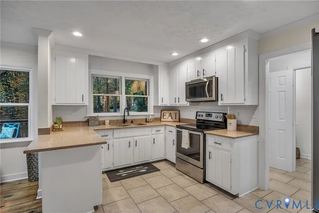 a kitchen with stainless steel appliances granite countertop a stove top oven a sink dishwasher and a refrigerator with wooden floor