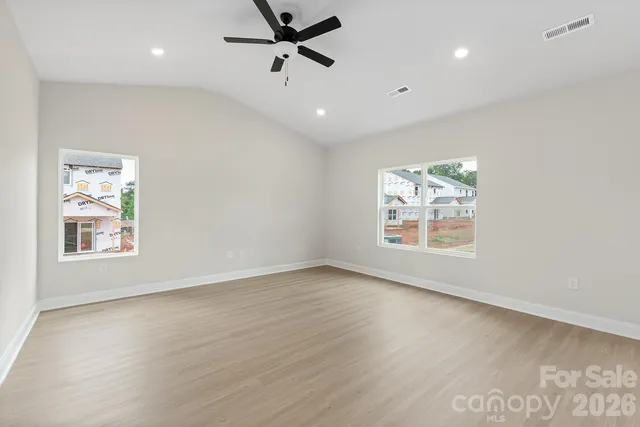 an empty room with wooden floor fan and windows