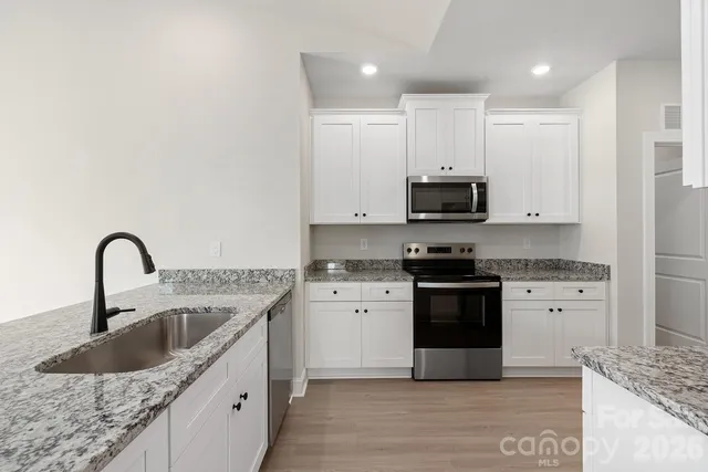a kitchen with stainless steel appliances granite countertop a sink and a stove top oven