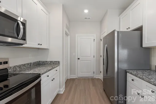 a kitchen with stainless steel appliances granite countertop a refrigerator and a stove top oven