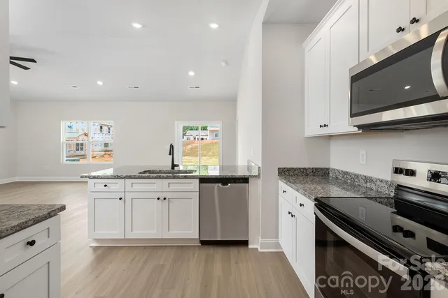 a kitchen with granite countertop cabinets stainless steel appliances and wooden floor