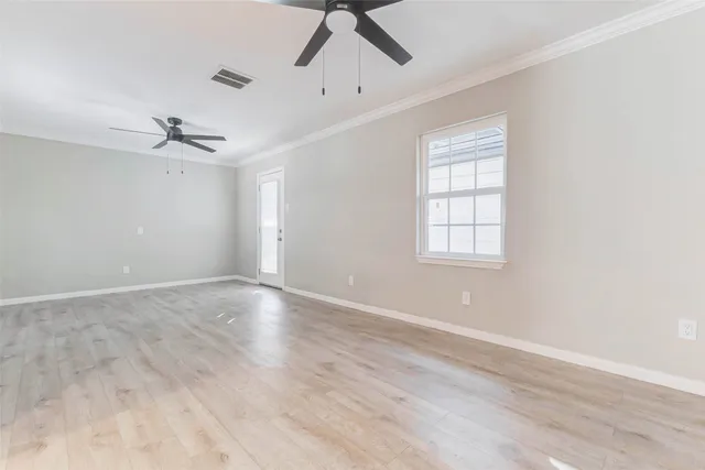 an empty room with wooden floor ceiling fan and windows