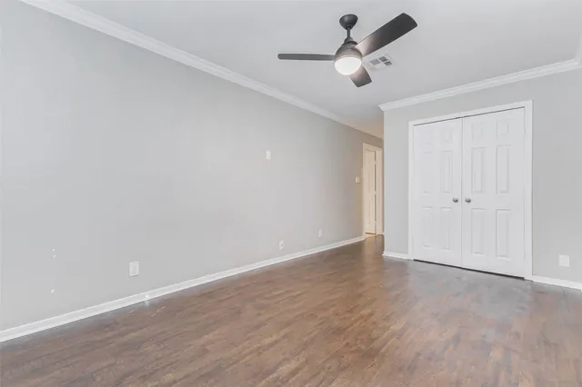an empty room with wooden floor and ceiling fan